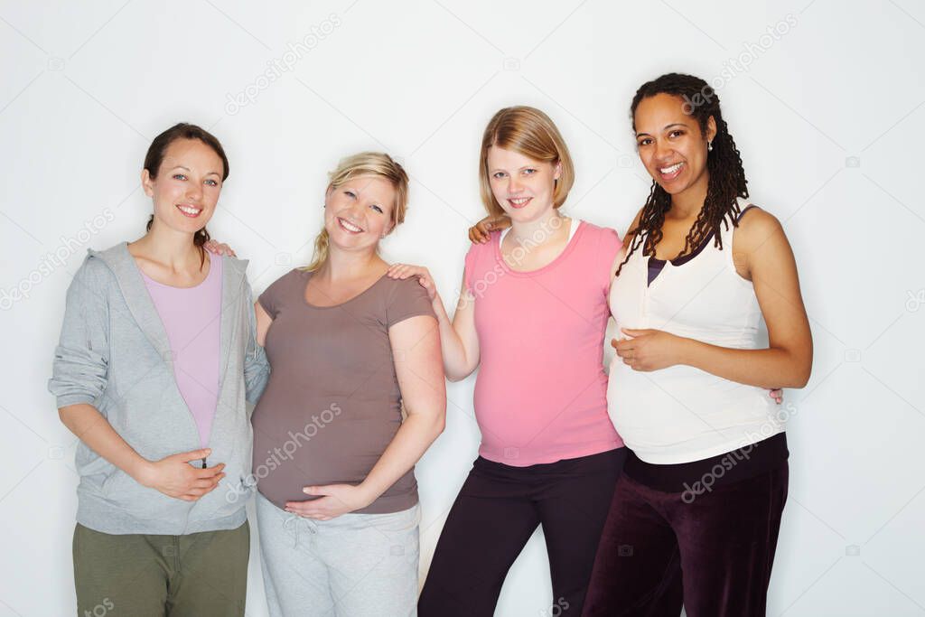 Bonding over the experience of pregnancy. Pregnant friends standing together while isolated on white.