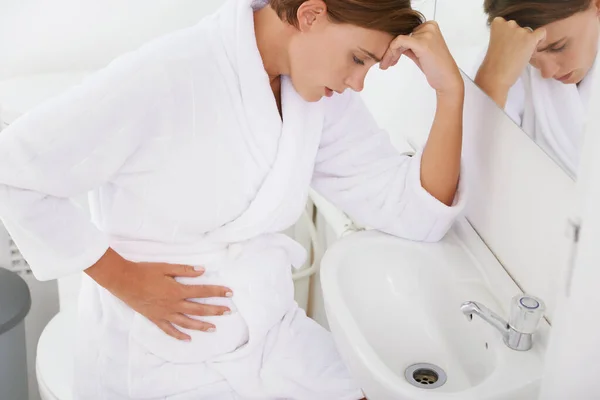 Bojuje s ranní nevolností. Těhotná žena zápasící s ranní nevolností v koupelně. — Stock fotografie