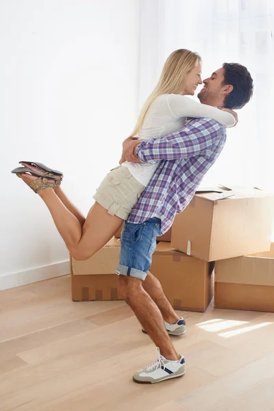 Feliz de estar en casa. Un hombre feliz recogiendo a su esposa en su nuevo hogar con cajas en el fondo. — Foto de Stock