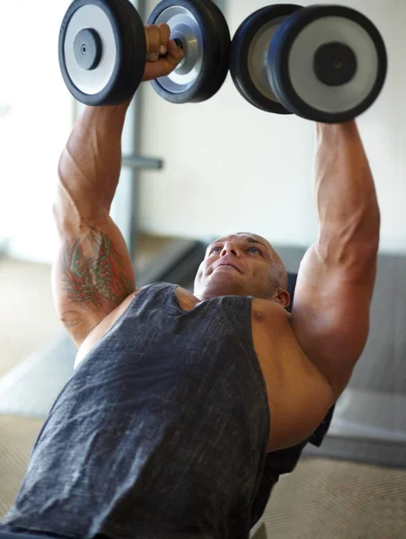 Concentra-te na sessão de treino. Tiro de um fisiculturista masculino levantando pesos no ginásio. — Fotografia de Stock