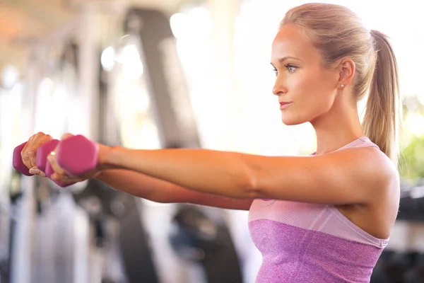 Het wordt nooit makkelijker, je wordt alleen maar sterker. Schot van een jonge vrouw die gewichten optilt. — Stockfoto