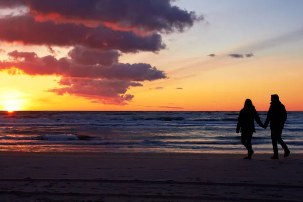 彼らは楽園を見つけた。夕暮れ時にビーチで散歩に行くカップルのシルエット. — ストック写真