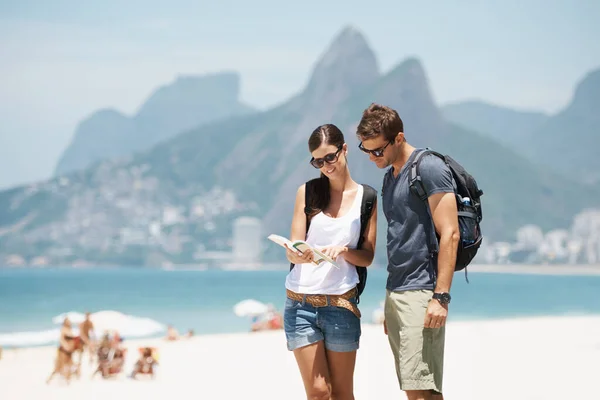 Отримання наших підшипників у раю. Знімок молодої пари, дивлячись на карту, стоячи на пляжі . — стокове фото