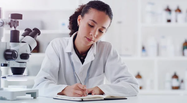 Untersuchung einer Angelegenheit nach der anderen. Aufnahme eines jungen Wissenschaftlers, der Notizen schreibt, während er in einem Labor arbeitet. — Stockfoto