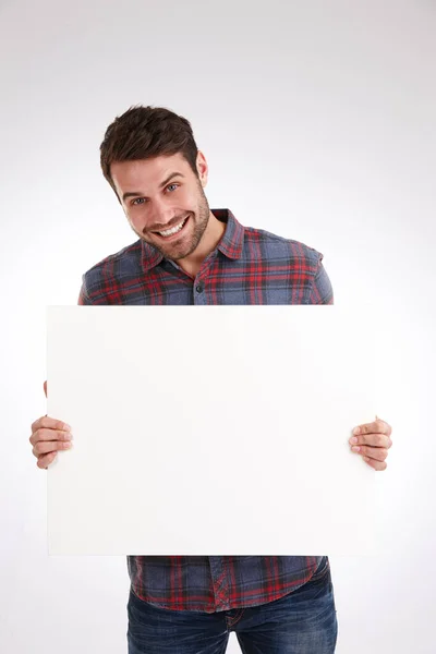 É disto que estou a falar. Estúdio tiro de um jovem sorridente segurando um cartaz branco em branco. — Fotografia de Stock