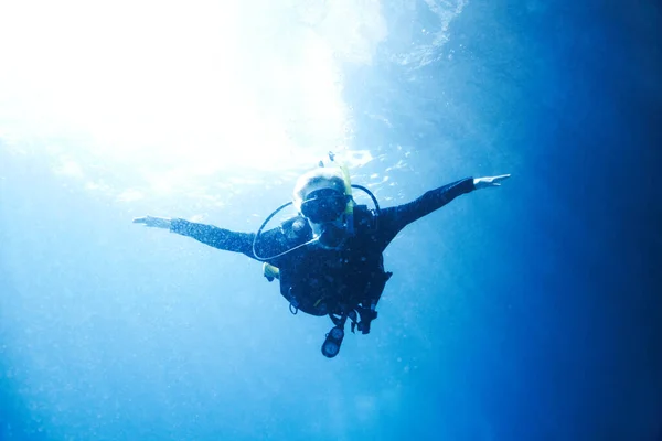 Svävar i havets djup. En dykare kommer ner mot dig med armarna vidöppna - Copyspace. — Stockfoto