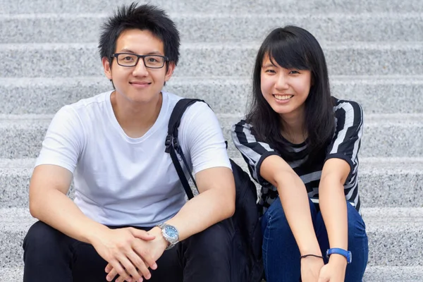 Vi älskar universitetet. Två unga studenter sitter utanför tillsammans. — Stockfoto