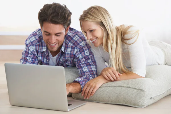Necesita un sofá nuevo Está a tan solo un clic. Una feliz pareja joven tirada en el suelo en casa y usando un ordenador portátil juntos. — Foto de Stock