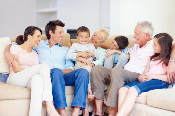Três gerações reúnem-se felizes. Três gerações de família sentadas juntas carinhosamente no sofá do lounge. — Fotografia de Stock