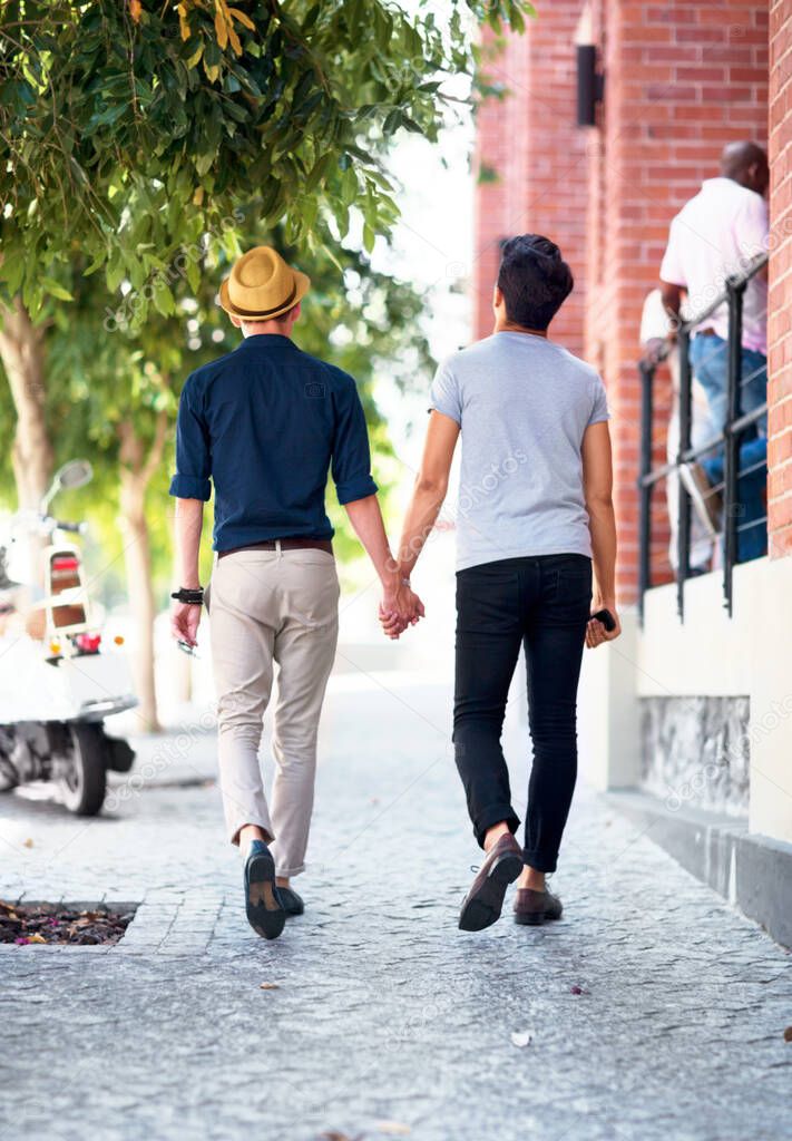 Love has no restrictions. Shot of a young gay couple waling outdoors while holding hands.
