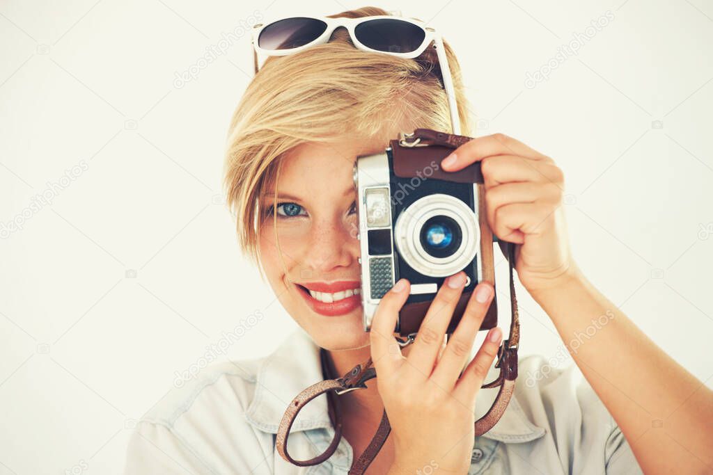 The moment might be gone but a memory lasts forever. Portrait of an attractive young woman standing with her camera in studio.