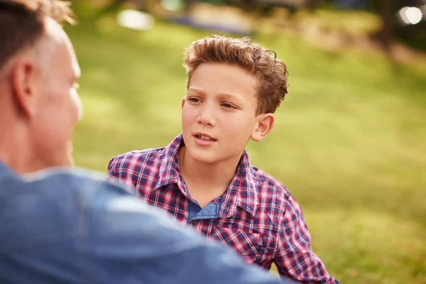 お父さんとの心の会話。公園に横たわっている間に父と息子が一緒に話しているのを撮影しました. — ストック写真