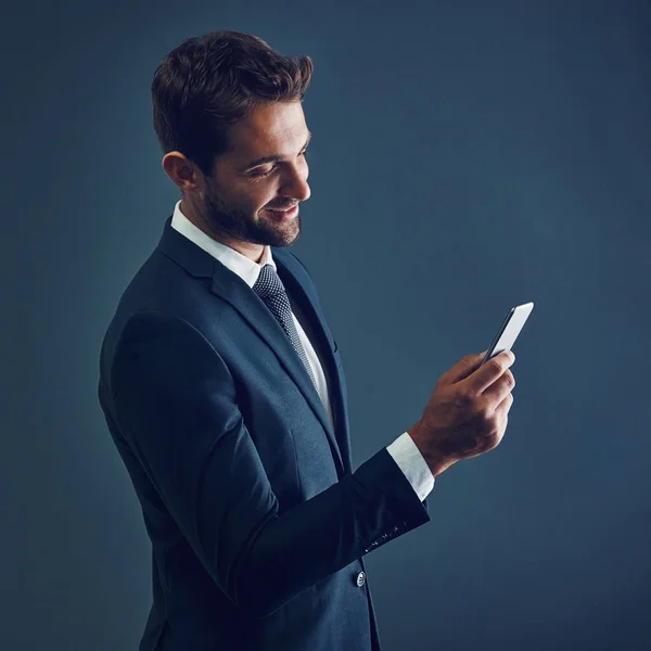 Haz la conexión que te llevará hacia adelante. Captura de estudio de un joven hombre de negocios guapo usando un teléfono celular sobre un fondo oscuro. — Foto de Stock
