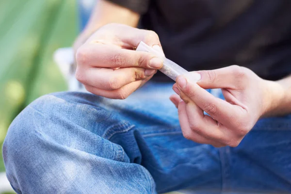 Todo tiene un portal. Una inyección de una persona irreconocible rodando un porro grande de marihuana. — Foto de Stock