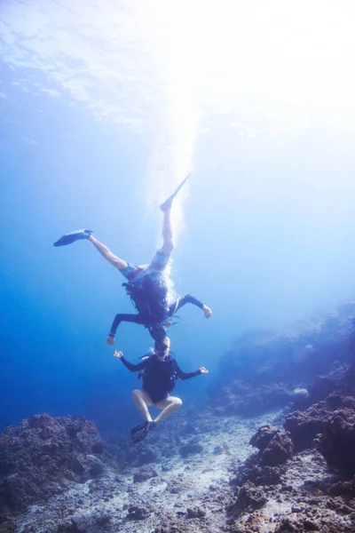 Подводные эскапады. Два плавучих ныряльщика с аквалангом дурачатся под водой голова к голове и вверх ногами - Copyspace. — стоковое фото