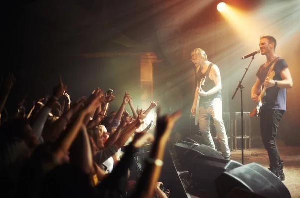 Shot of a crowd of music fans reaching up at a guitarist on stage. This concert was created for the sole purpose of this photo shoot, featuring 300 models and 3 live bands. All people in this shoot — Stock Photo, Image