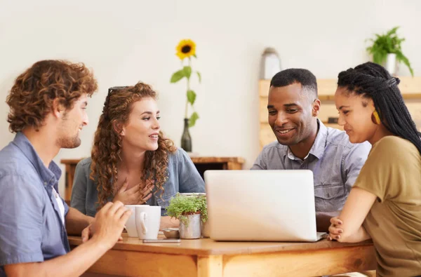 En bonne compagnie. Un groupe d'amis assis ensemble dans un café avec un ordinateur portable. — Photo