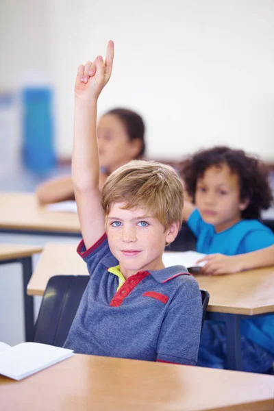 Svar på dit spørgsmål. Portræt af en ung dreng, der holder hånden oppe i klassen for at besvare et spørgsmål. - Stock-foto