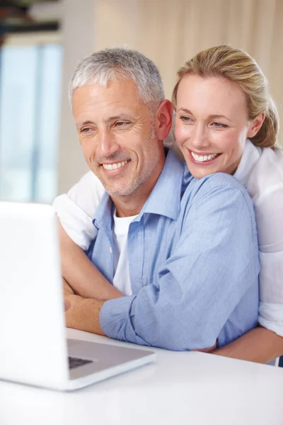 Abbracciare il mondo digitale. Una moglie che abbraccia il marito mentre lavora sul portatile. — Foto Stock