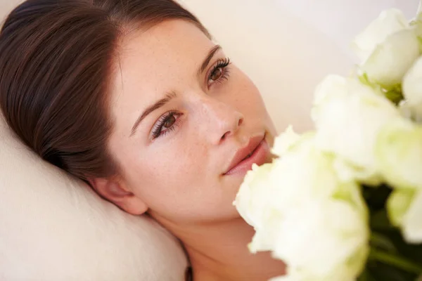 Να ερωτευτείς. Μια όμορφη νεαρή γυναίκα ξαπλωμένη και κρατώντας ένα μπουκέτο λευκά τριαντάφυλλα στο στήθος της. — Φωτογραφία Αρχείου