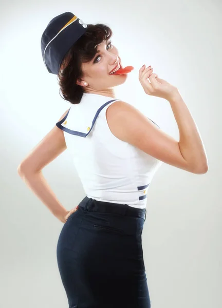 Naughty in naughtical. A sailor pinup girl posing against white with a lollipop. — Stock Photo, Image