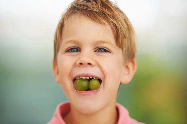 Its a mouthful of fruitiness. Shot of a boy stuffing two grapes in his mouth. — Stock Photo, Image