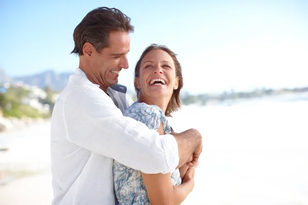 Охоплює їхнє життя і любов. Зрілий чоловік обіймає свою щасливу дружину позаду, коли вони стоять на пляжі . — стокове фото