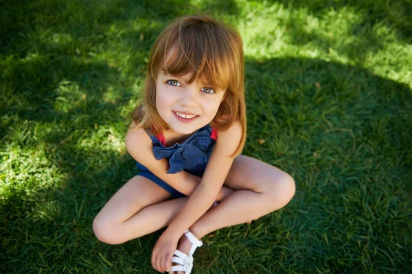 Zonnige dag plezier. Shot van een schattig klein meisje glimlachen terwijl liggend op gras. — Stockfoto