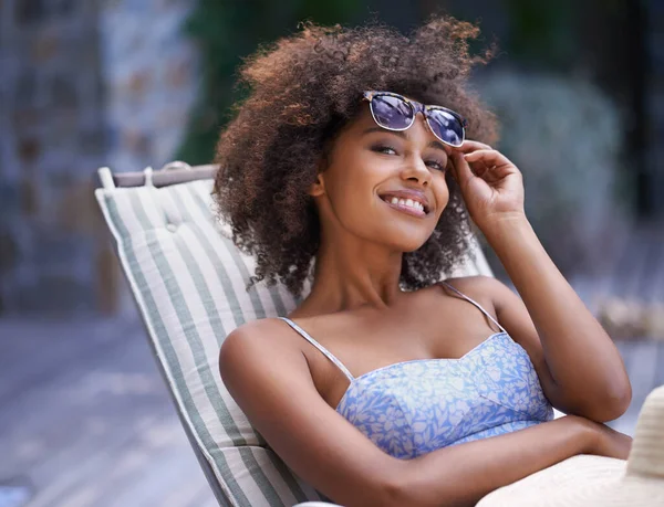 E 'cosi' che voglio passare ogni giorno. Attraente femminile etnica rilassante sulla sedia a sdraio reggendo i suoi occhiali da sole. — Foto Stock