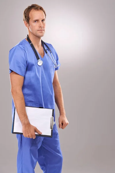 Se toma en serio la cirugía. Retrato de estudio de un guapo cirujano masculino sosteniendo un portapapeles. — Foto de Stock