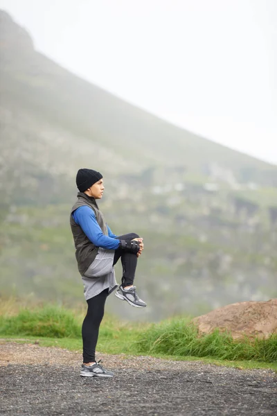 Ademend in de frisse lucht.... Volledige lengte van een jonge jogger uitrekken in de ochtend en genieten van het uitzicht. — Stockfoto