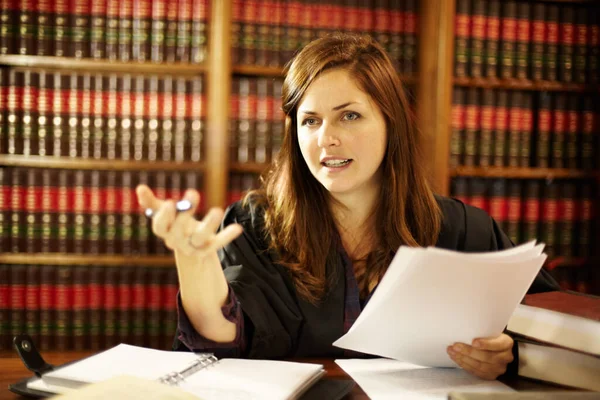 Θέτοντας μια νομική προτεραιότητα. Ελκυστική νεαρή δικαστής κάθεται στο γραφείο της συζητώντας το νόμο. — Φωτογραφία Αρχείου