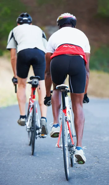 Ik probeer de leider te passeren. Achteraanzicht van twee renners die samen over een landelijke weg fietsen. — Stockfoto