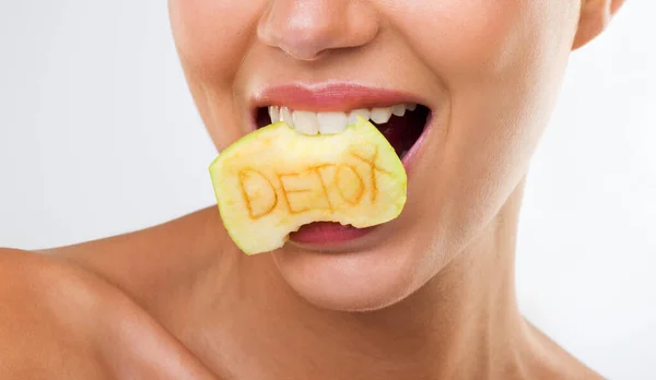 Mari kita memiliki hari detoks. Seorang wanita muda menggigit apel dengan kata detox tertulis di atasnya. — Stok Foto