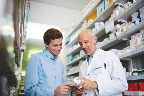 Este es el que quieres. Fotografía recortada de un guapo farmacéutico varón maduro ayudando a un cliente en la farmacia. —  Fotos de Stock