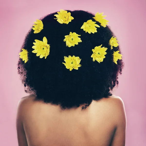 Zo natuurlijk als het maar kan. Rearview shot van een vrouw die staat met bloemen in haar haar. — Stockfoto