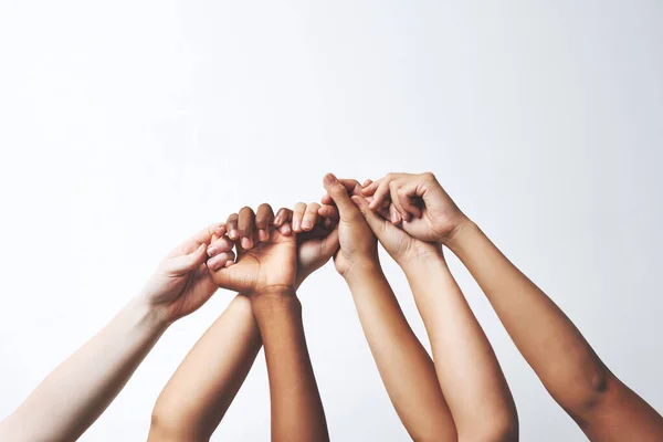 Let your hands do the talking. Studio shot of a group of unrecognizable people holding each others thumbs while their hands are raised. — Stock Photo, Image