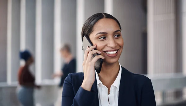 Los nuevos clientes están a solo una llamada. Fotografía de una joven empresaria usando un teléfono inteligente contra un fondo de la ciudad. — Foto de Stock