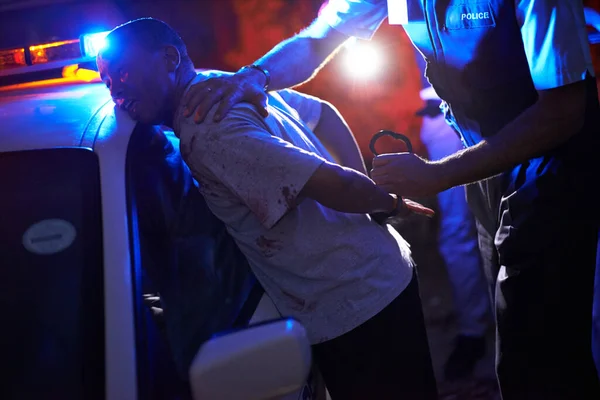 Dienen und schützen. Schuss eines Polizisten, der einen Verdächtigen an seinem Streifenwagen fesselt. — Stockfoto