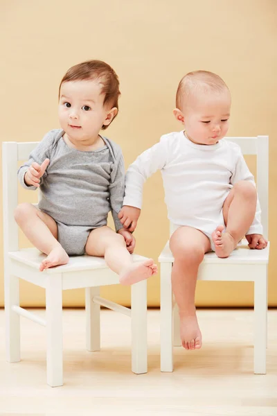 이브는 재미로 서로를얻었어. 귀여운 아기 두 명 이 의자에 앉아 카메라 앞에서 웃고 있는 사랑 스러운 사진. — 스톡 사진
