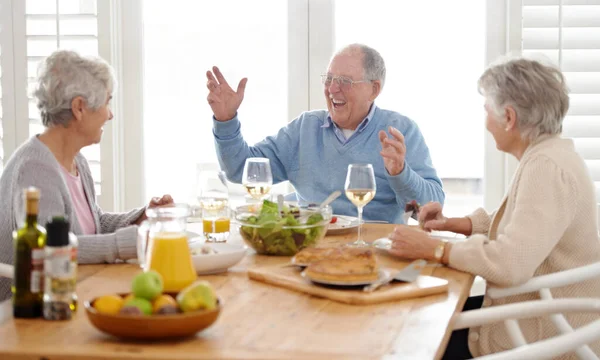 Hidup dimulai saat pensiun. Seorang pria senior dan dua wanita senior menikmati makan siang. — Stok Foto