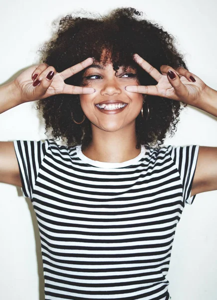 Divertimento su fleek. Studio foto di una giovane donna giocosa che mostra il segno della pace su uno sfondo grigio. — Foto Stock