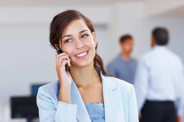 Jonge vrouwelijke leidinggevende aan het praten op mobiele telefoon kantoor. Closeup van jonge vrouwelijke uitvoerende spreken op mobiele telefoon met personeel op de achtergrond. — Stockfoto