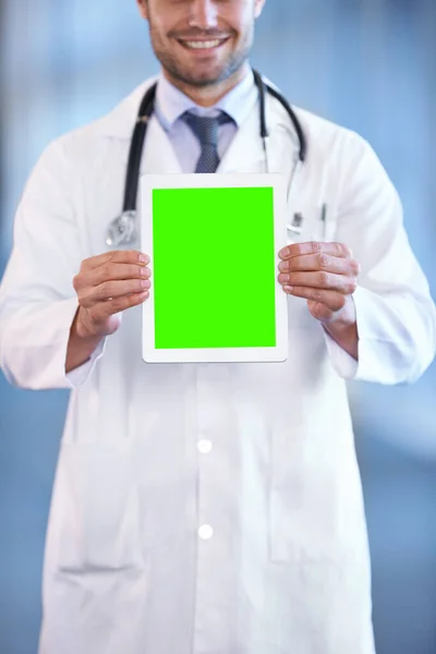 Η τελευταία λέξη της τεχνολογίας υγείας. Φωτογράφηση ενός νεαρού ευτυχισμένου γιατρού που κρατάει ένα ψηφιακό tablet έτσι ώστε η οθόνη να βλέπει την κάμερα. — Φωτογραφία Αρχείου