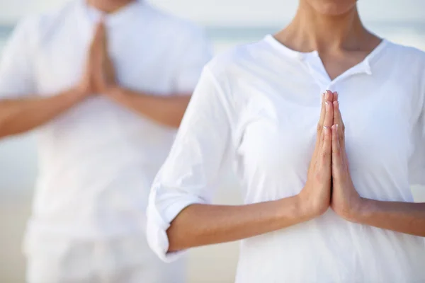 De kunst van meditatie. Gehakt schot van twee mensen die mediteren op het strand. — Stockfoto