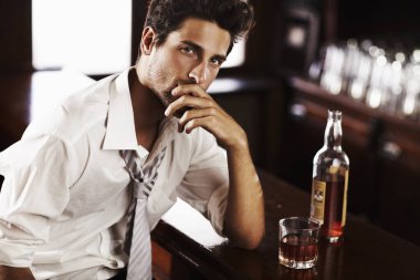 Professional at work, sophisticated after it - Modern Living. A handsome young man winding down after work with a drink at the bar. clipart