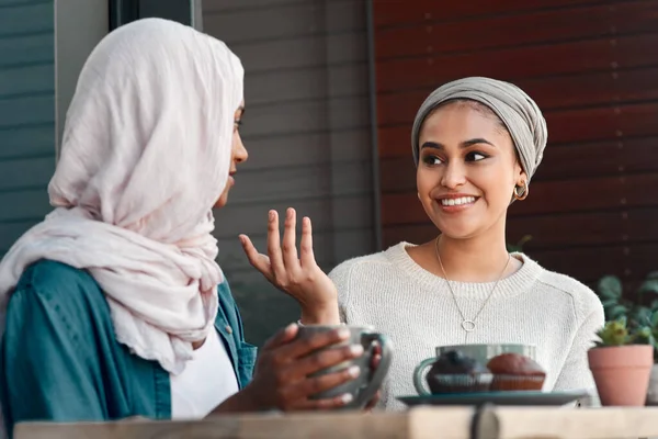 Ze hebben veel om over te praten. Gehakt schot van twee aanhankelijke jonge vriendinnen die een praatje in een coffeeshop terwijl gekleed in hijab. — Stockfoto