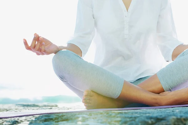 Absorberar naturen fred. En ung kvinna som utför yoga på stranden i sommarsolen. — Stockfoto