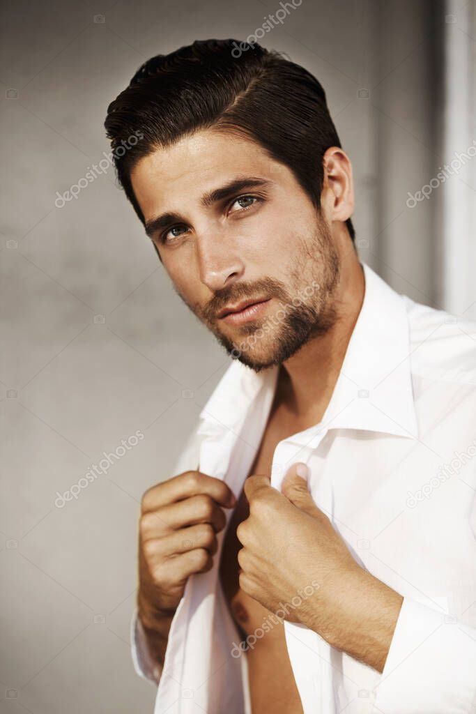 A real man makes the clothes work for him. Young, attractive male dressing while looking at camera - portrait.
