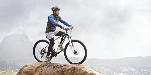 Een mountainbiketocht maken. Een jongeman op een mountainbike met een prachtig uitzicht op de achtergrond. — Stockfoto